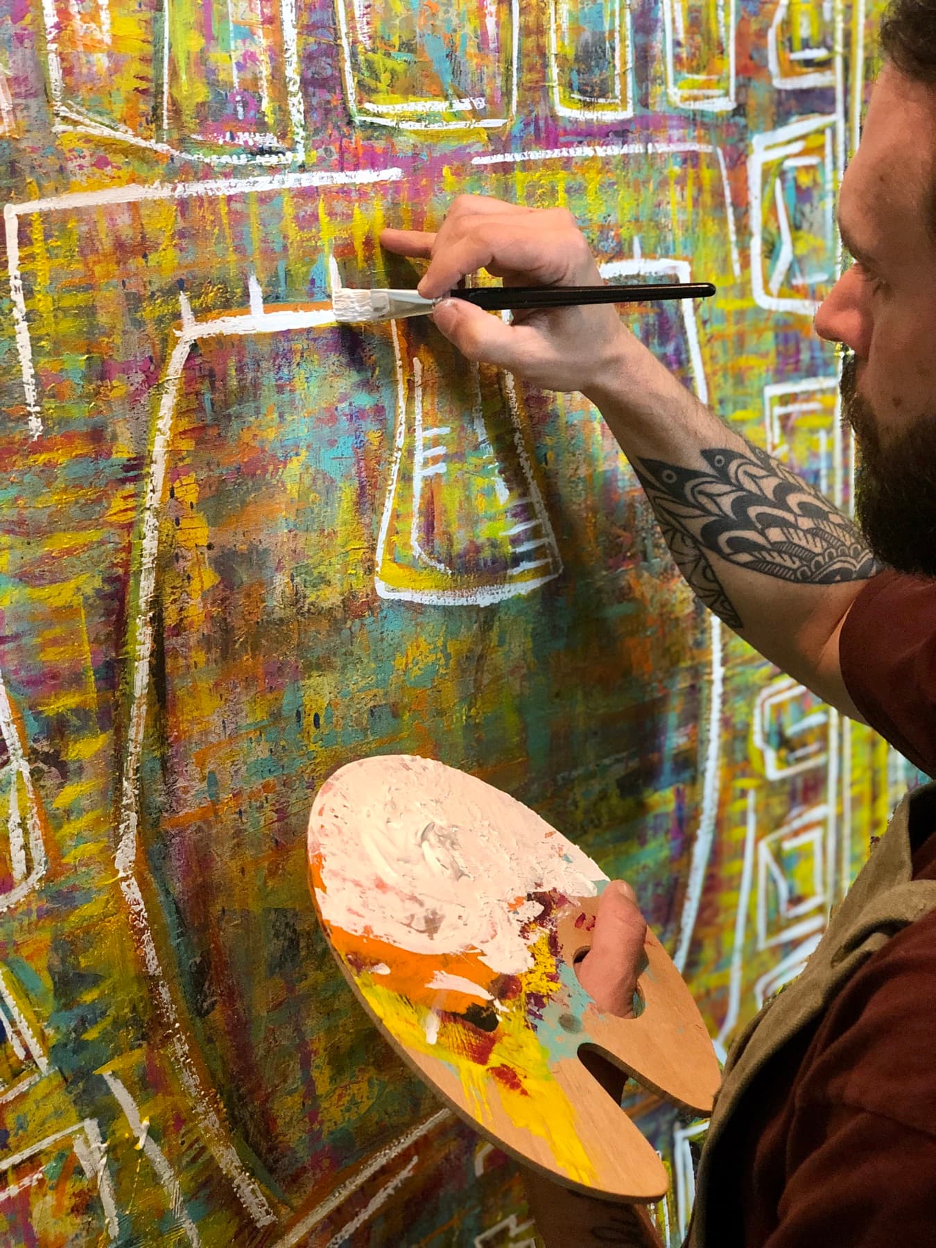 Dylan Yarter painting at the easel, palette in hand, laying white line over color