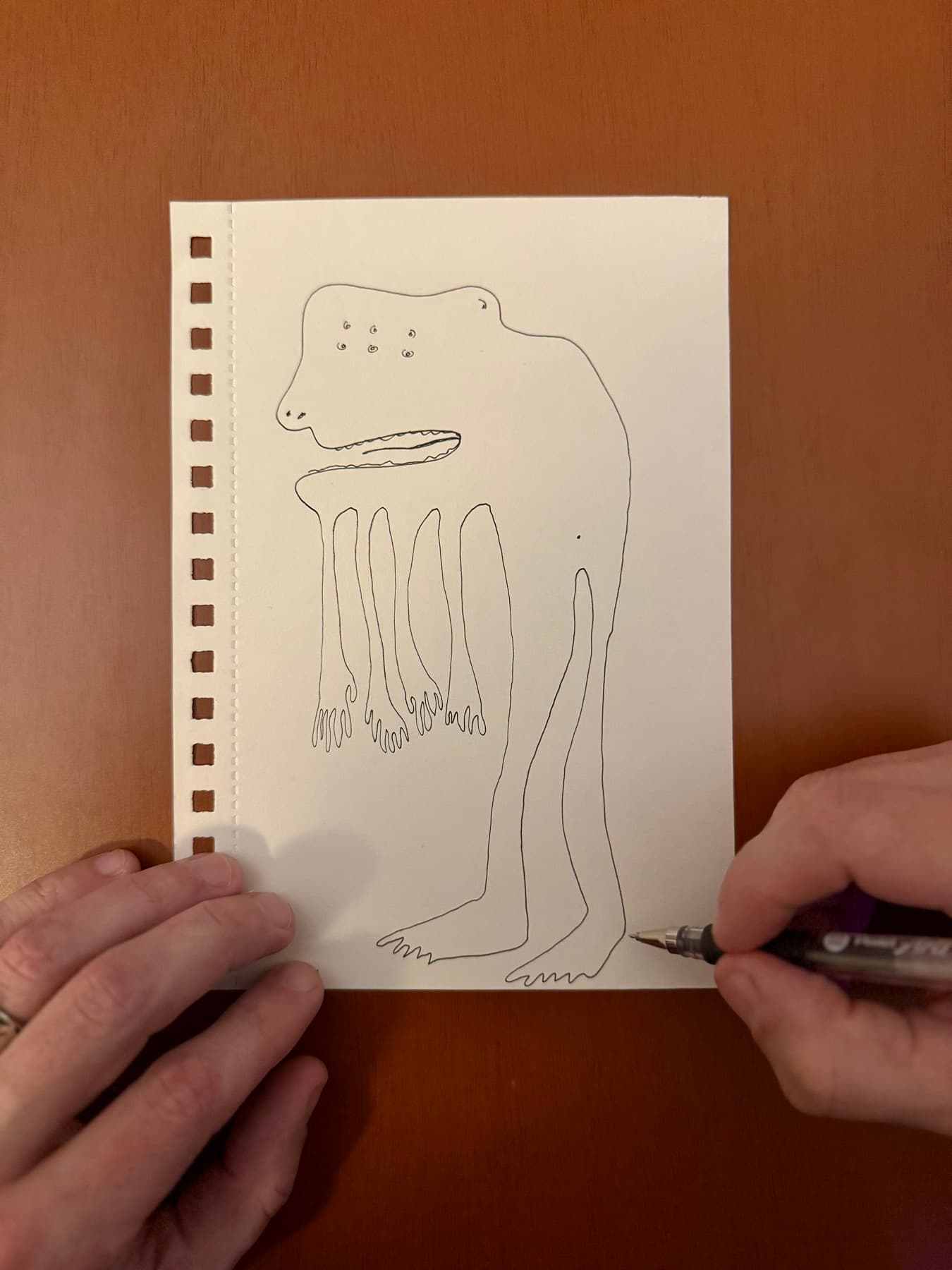 Dylan Yarter drawing a creature in a single continuous ink line on paper