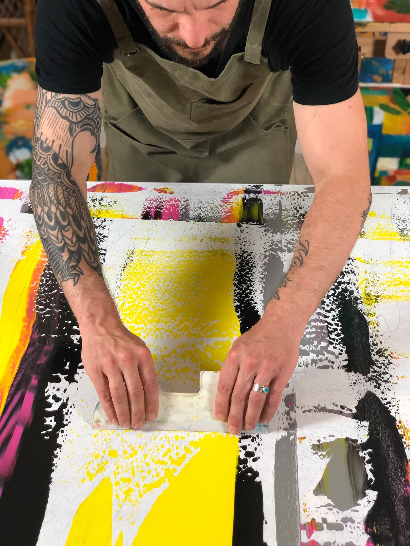 Pulling a scraper across a canvas in the studio