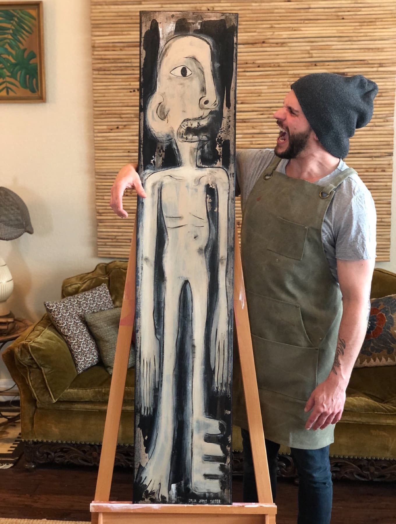 Dylan Yarter standing beside his tall black and white painting Aborigine